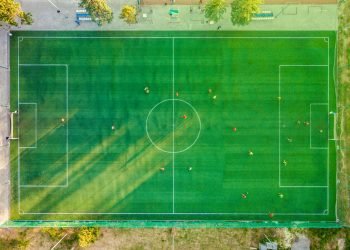 Aerial shot of a soccer game with players on a vibrant green field.